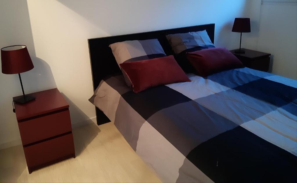 a bedroom with a bed with pillows and a red night stand at RESIDENCE APPART CENTRE VILLE LORIENT Calme Garage in Lorient