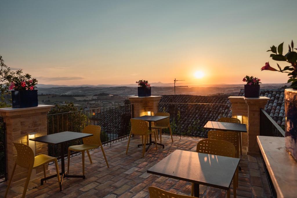 d'une terrasse avec des tables et des chaises et un coucher de soleil. dans l'établissement OGNISSANTI GuestHouse & Suites, à Fermo
