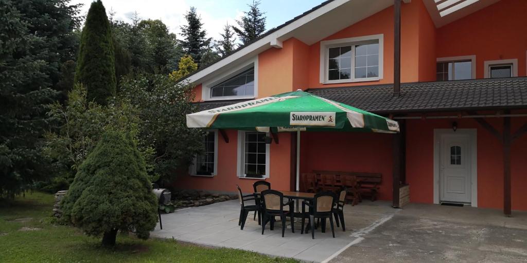 - une table avec des chaises et un parasol vert devant une maison dans l'établissement APARTMÁNY POD ČERCHOVEM, à Trhanov