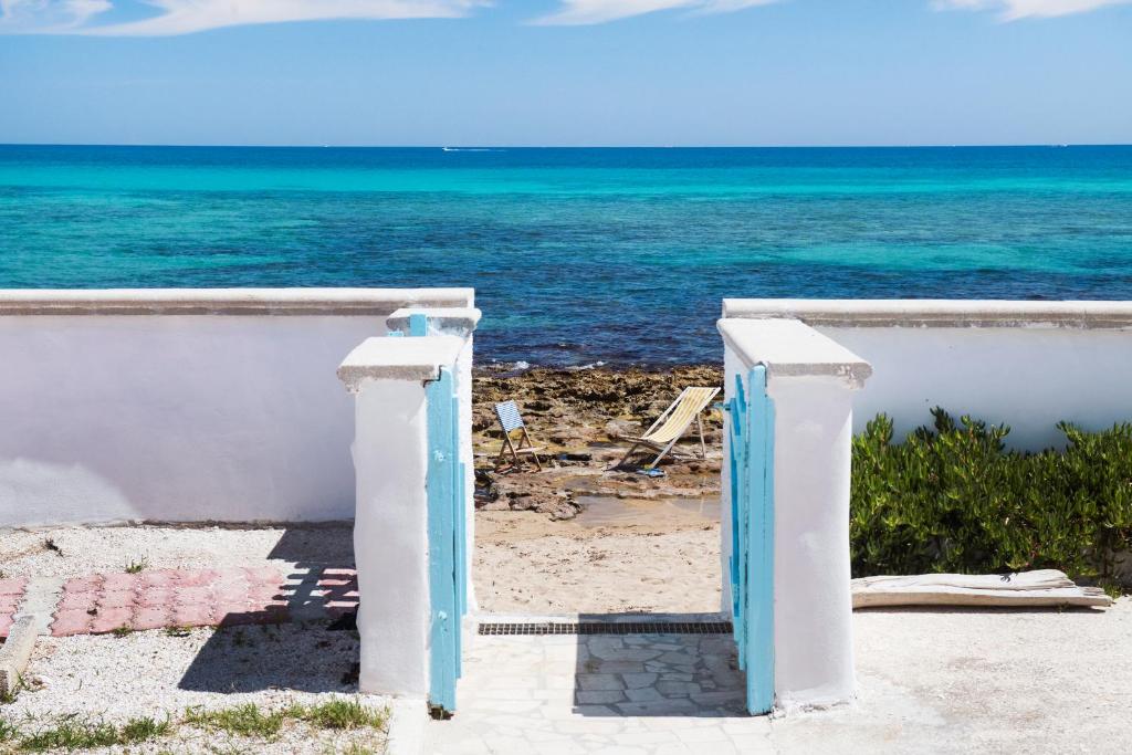 un cancello per la spiaggia con l'oceano sullo sfondo di Apulianstay- Villa elvira a Faccia di Trippa