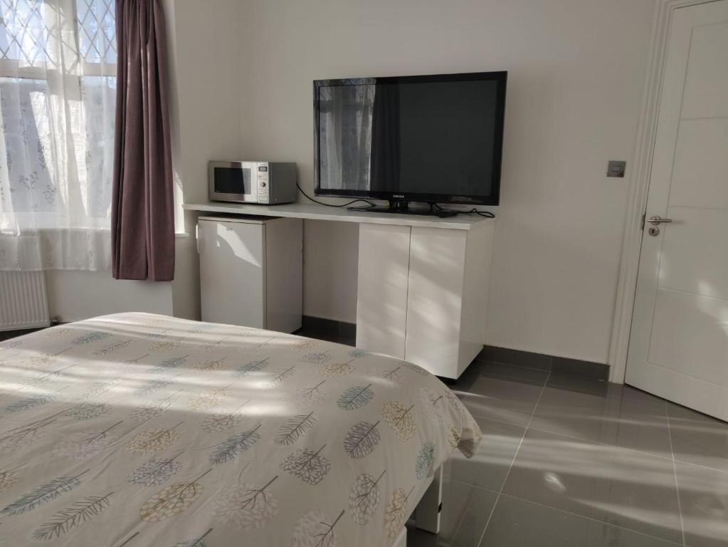 a room with a tv and a table with a bed at Stunning Double Room in Harrow Wembley - Khoob House in London