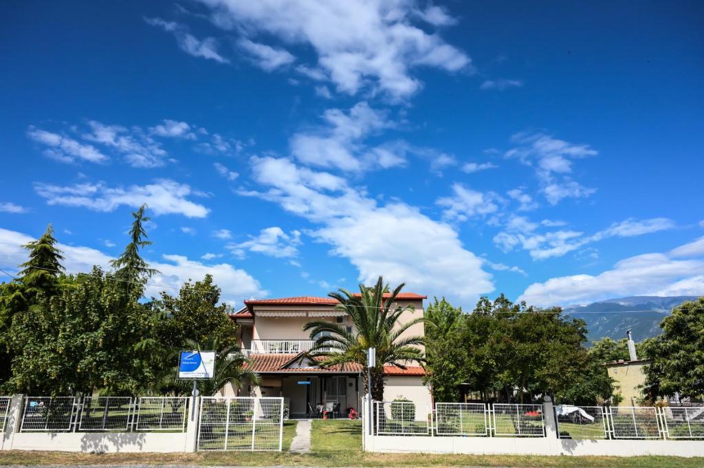 a house with a fence and a blue sky at Priona Rooms in Paralía Skotínis