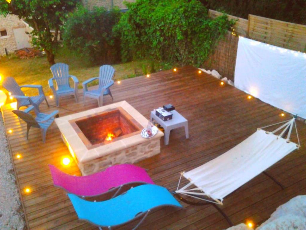 een houten terras met stoelen en een vuurplaats bij Chez Petit in Argançon