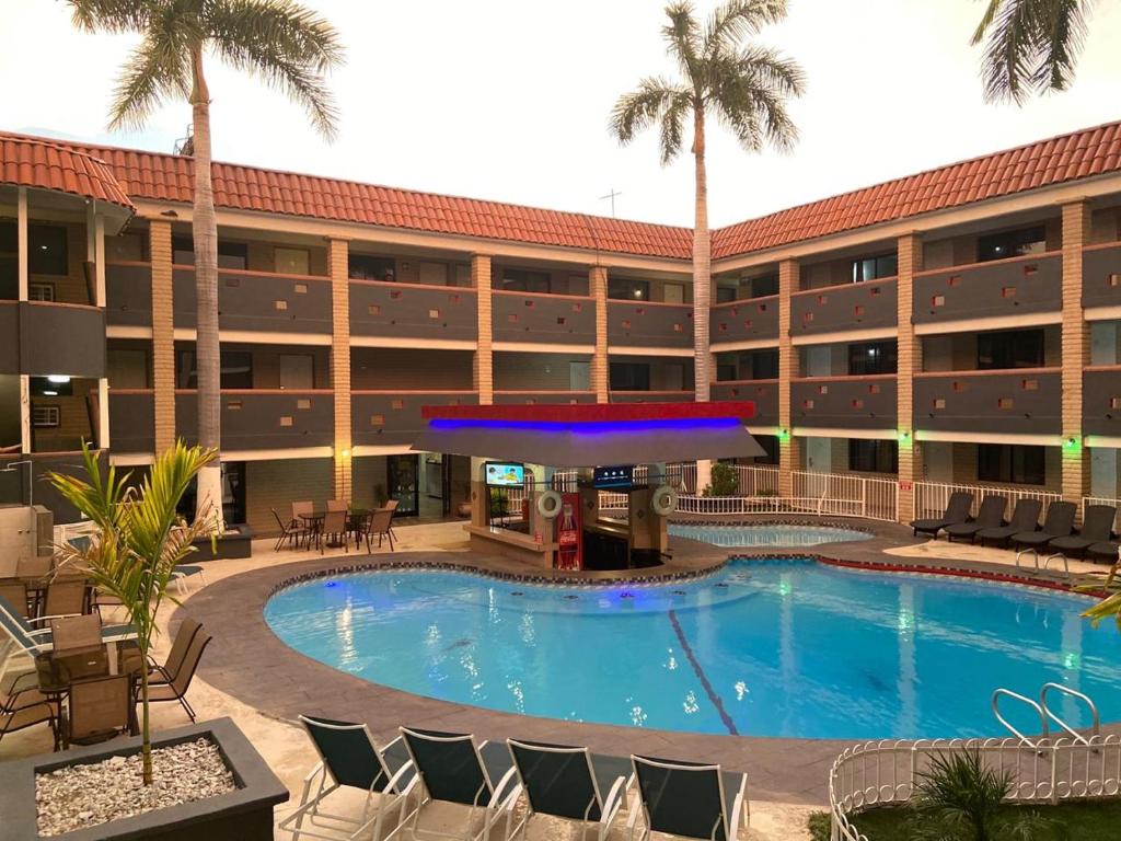 a pool in front of a hotel with palm trees at Hotel La Finca in Hermosillo