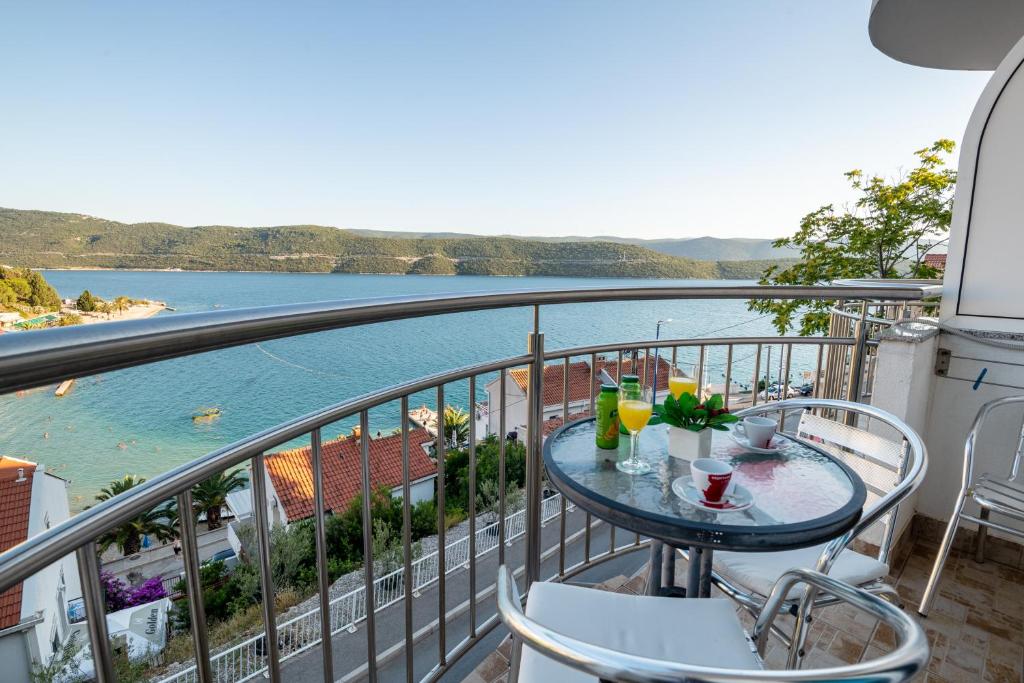 uma varanda com mesa e cadeiras e vista para a água em Motel Jadranka em Neum