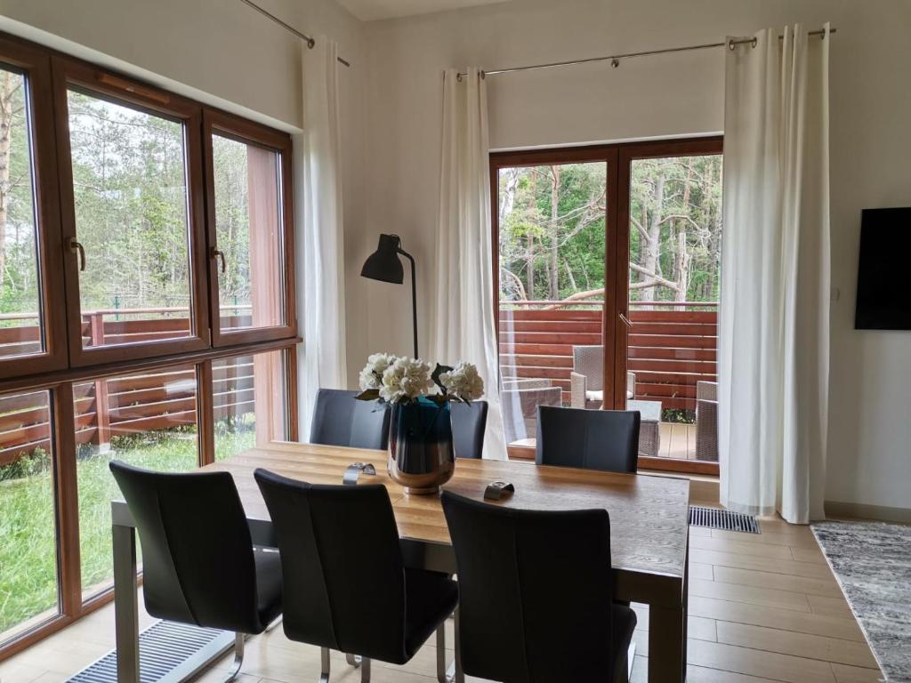 jadalnia ze stołem, krzesłami i oknami w obiekcie LUX Apartment Karina Porta Mare w Dziwnówku