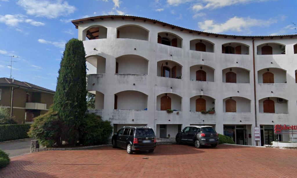 dwa samochody zaparkowane przed dużym budynkiem w obiekcie Mattia's House on Garda Lake w mieście Peschiera del Garda