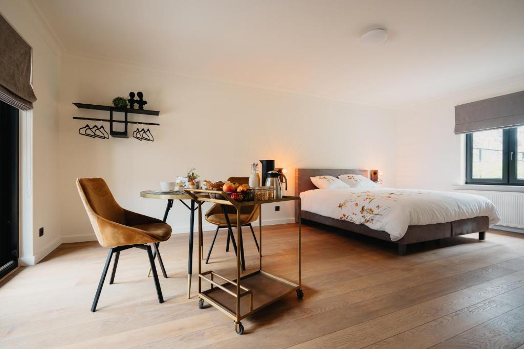 1 dormitorio con cama, escritorio y mesa en B&B 't Wilgenhuys en Lommel