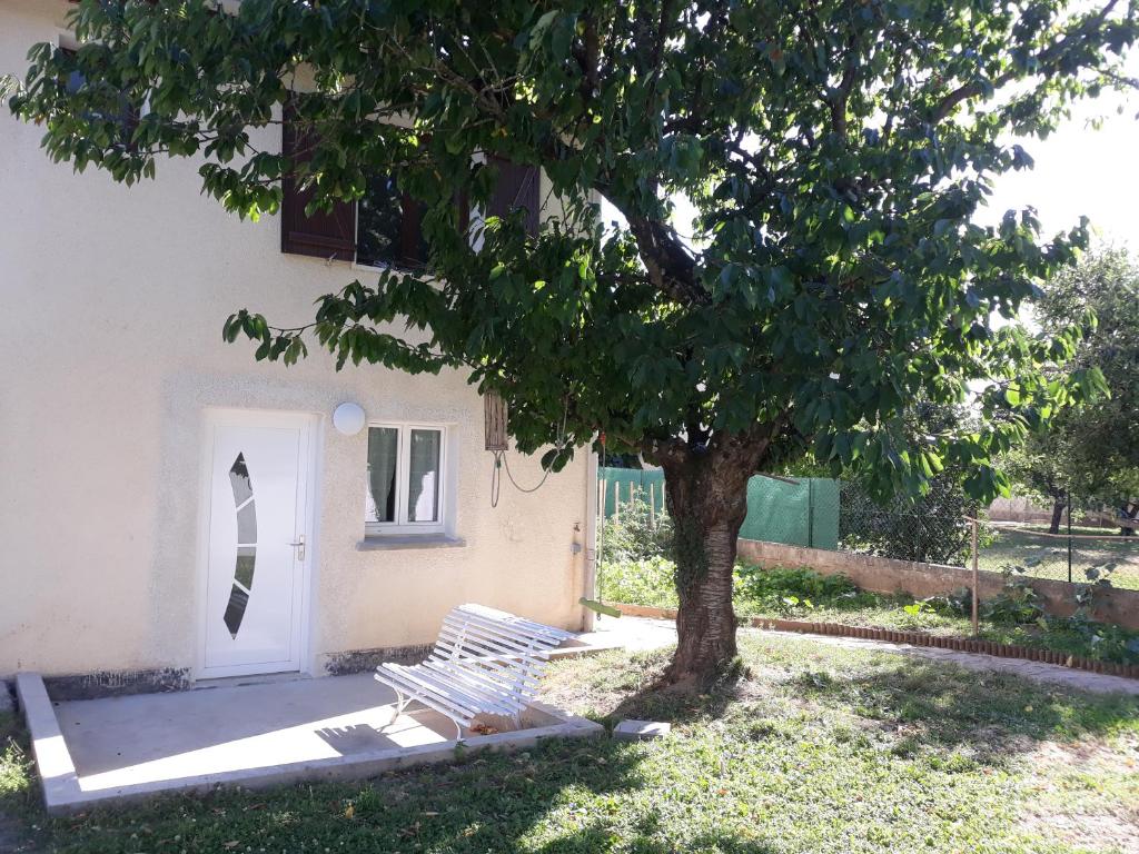 a white bench next to a tree next to a door at T2 courte durée in Jonage