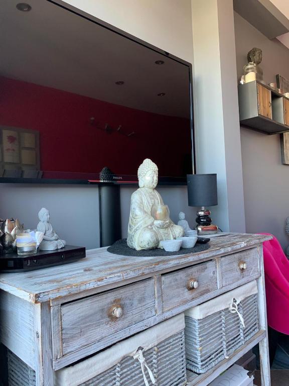 une commode en bois avec une statue assise au-dessus dans l'établissement Le Boudha Love, au Cap d'Agde