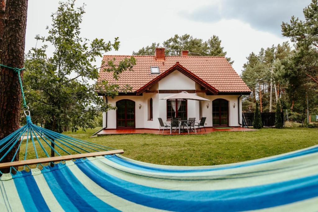 una casa con una hamaca delante en Pluski Dom "Ryś" nad J. Pluszne en Pluski