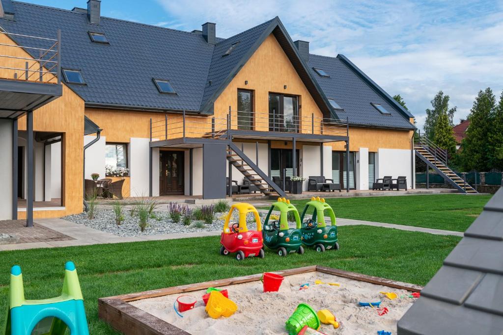 a house with a playground with toys in the yard at Róża Bałtyku - Apartamenty i Pokoje in Dębki