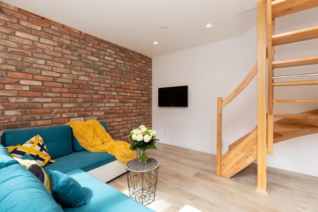 a living room with a blue couch and a brick wall at Domki Amare in Pobierowo