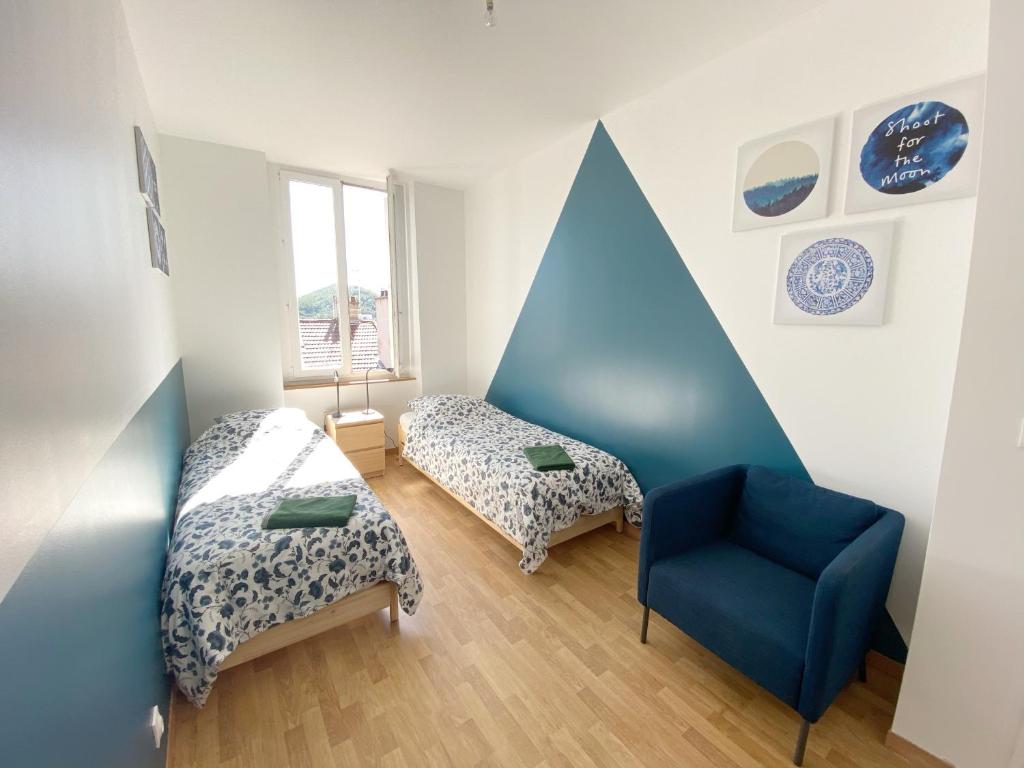 Cette chambre comprend 2 lits et une chaise bleue. dans l'établissement 022 CHIC & COSY GRAND APPART DUPLEX 92m2 WIFI SMART TV NETFLIX, à Saint-Étienne