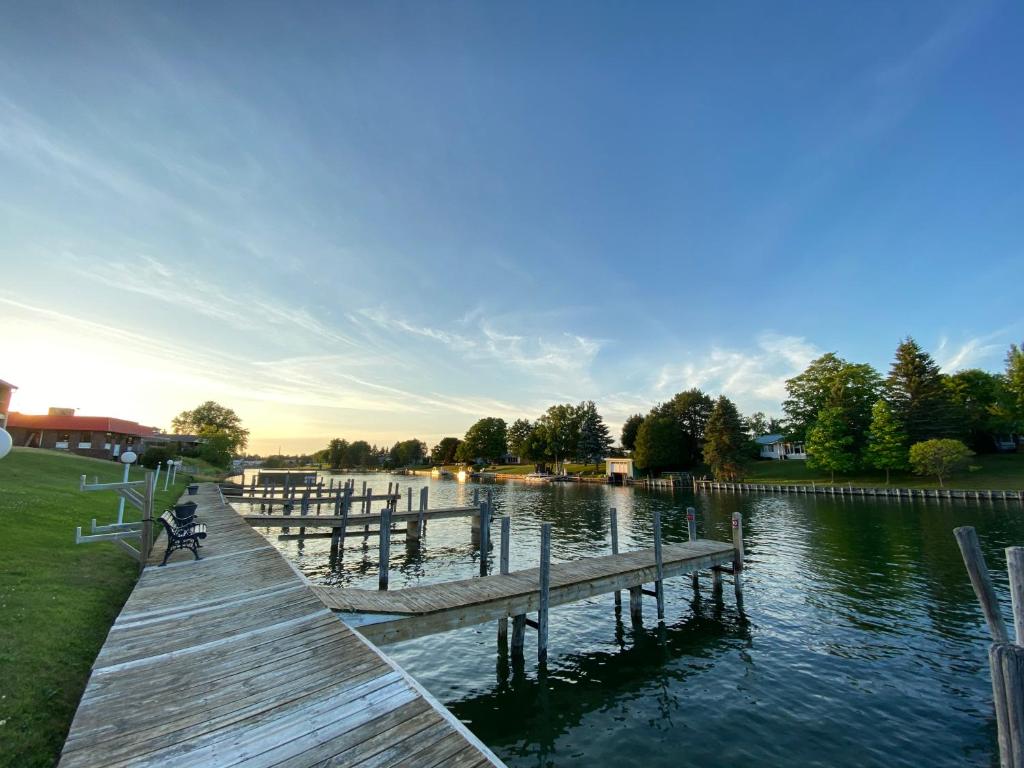 un muelle en un lago con una persona sentada en un banco en Fleetwood Inn Suites, en Cheboygan