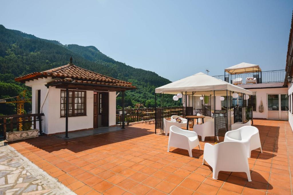 une terrasse avec des chaises blanches, une table et un parasol dans l'établissement Nations Gerês - Bed & Breakfast, à Gerês