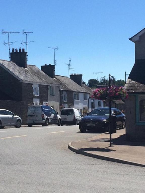 a street with cars parked in a small town at Glaslough Ramblers Rest in Monaghan