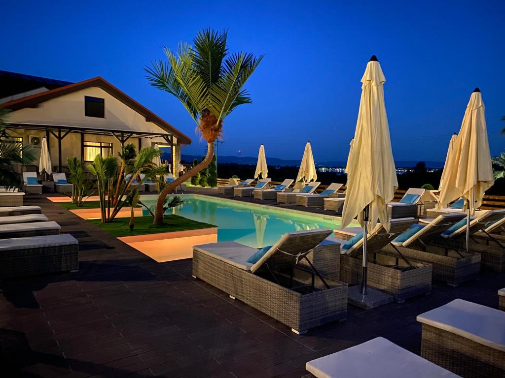 un resort con piscina con sedie e ombrelloni di Pensiunea Alexandra & SPA a Divici