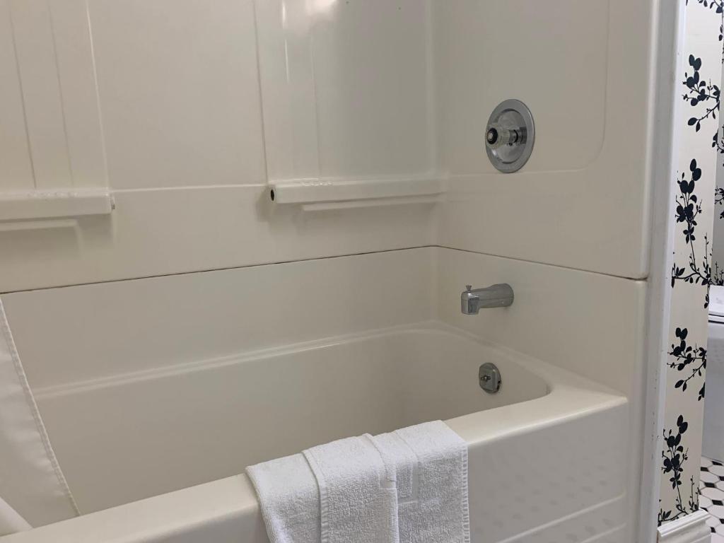 a white bathroom with a bath tub with a towel at Inn at the Falls in Bracebridge