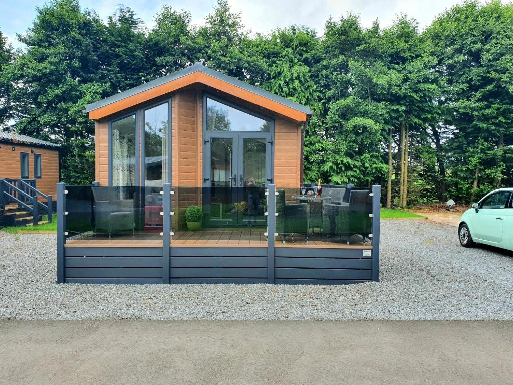 a small house with glass doors and a car at Grand Eagles Luxury Lodge, Auchterarder in Perth