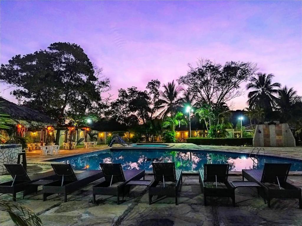 a swimming pool with chairs in front at Pousada Recanto dos Passaros in Balsas