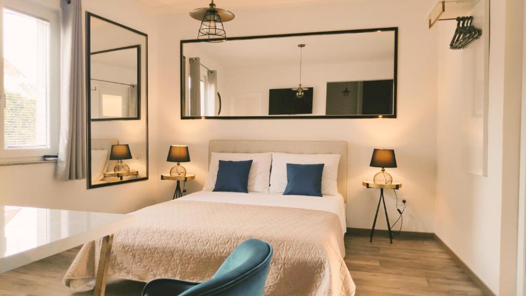 a bedroom with a bed with a mirror and a blue chair at Central Park Suites in Vodice