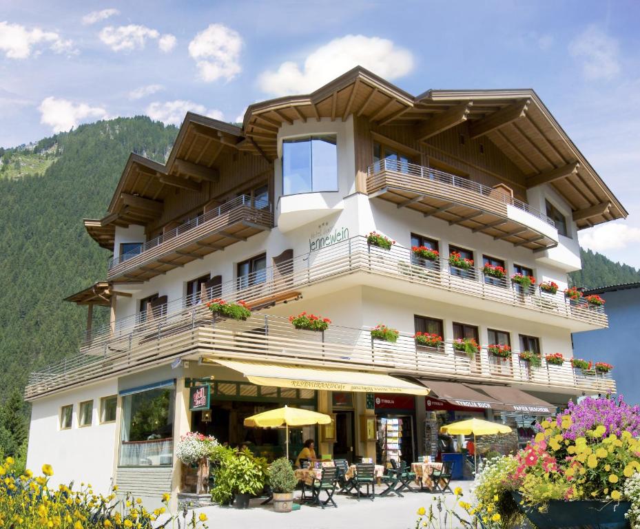 a building with a balcony and tables and chairs at Hotel Garni Jennewein in Mayrhofen