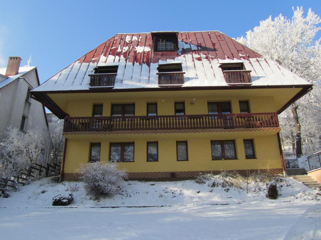 una casa gialla con tetto rosso nella neve di Willa Słoneczko a Duszniki Zdrój