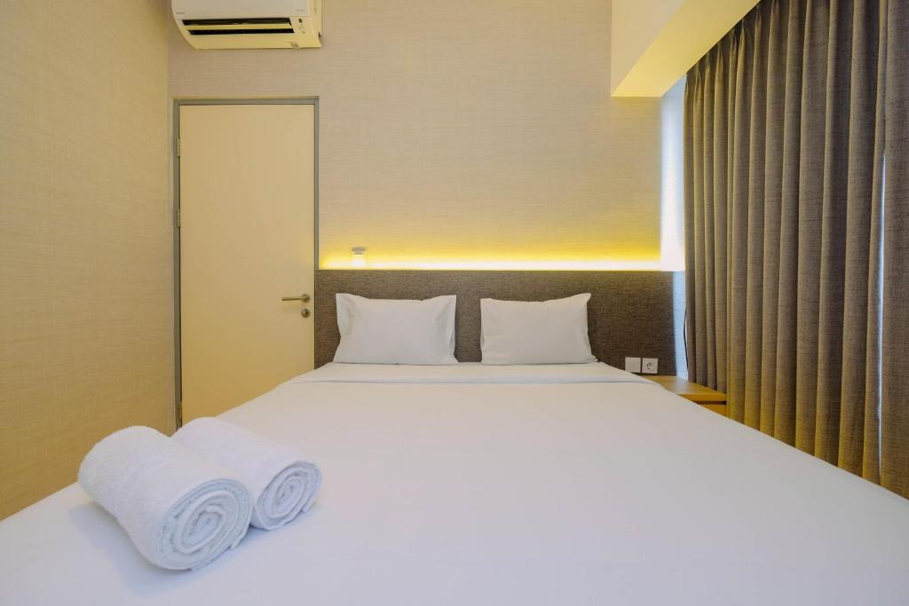 a bedroom with a large white bed with towels on it at Relax 3BR Apartment at M-Town Residence By Travelio in Tangerang