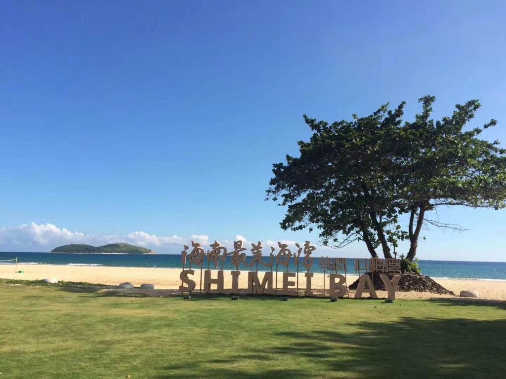 a bench on a beach with a tree and the ocean at Marcia's Guest House in Wanning