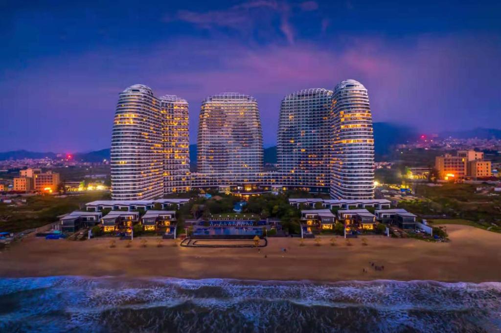 a group of tall buildings on a beach at night at Howard Johnson Sandalwoods Resort Huizhou in Huidong