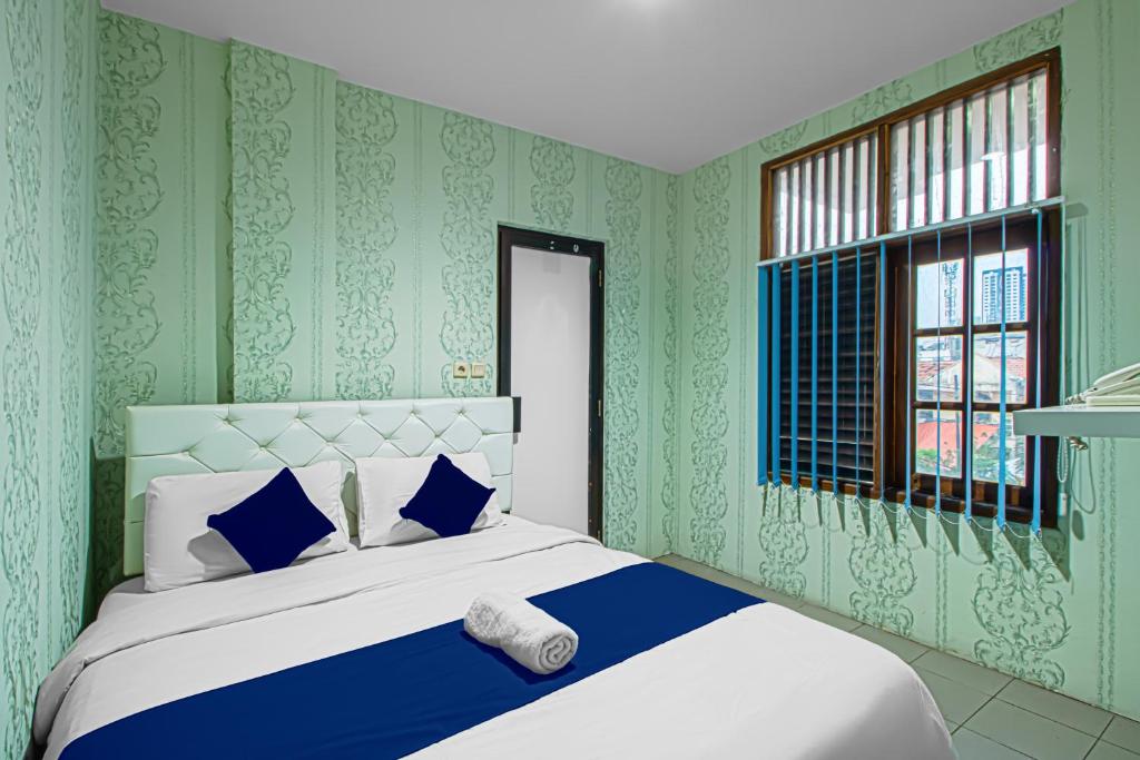 1 dormitorio con 1 cama con paredes azules y verdes en Bungur Inn Syariah, en Yakarta