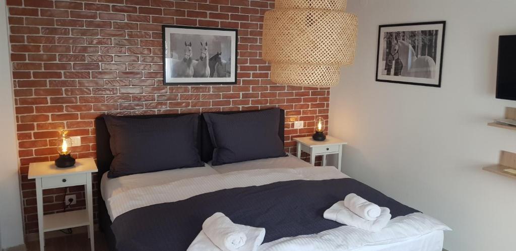 a bedroom with a brick wall and a bed with pillows at Studio apartman Relax in Đakovo