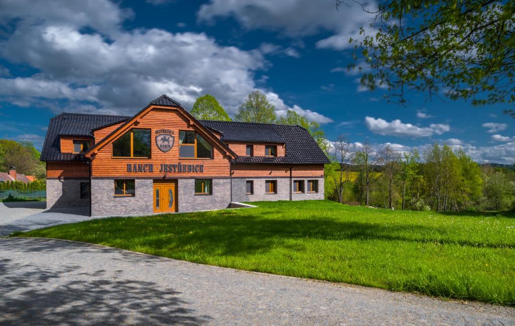 ein Haus auf einem Grasfeld mit einem Gebäude in der Unterkunft Ranch Jestřebice in Heřmaničky