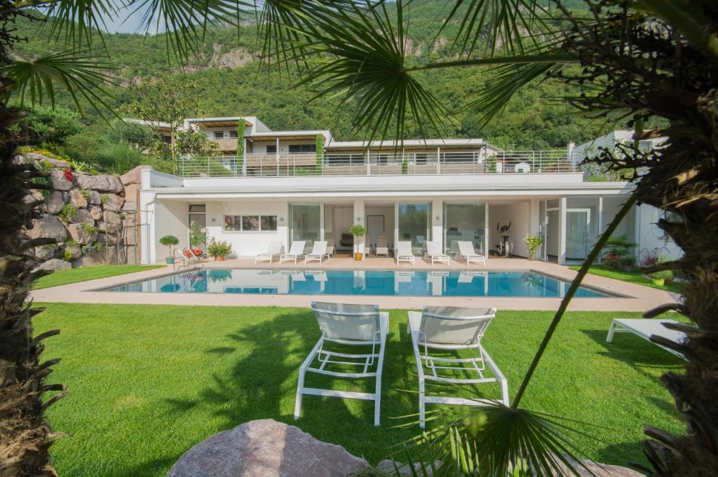una casa con piscina y 2 sillas de césped en Hidalgo Suites, en Merano