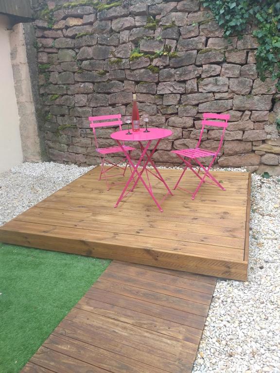 2 sillas rosas y una mesa en una terraza de madera en Gîte le Petit Muscat à Eguisheim, en Eguisheim