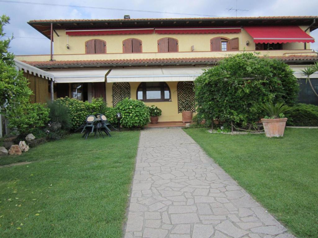 a house with a walkway in front of a yard at La Casa Gialla in Montignoso