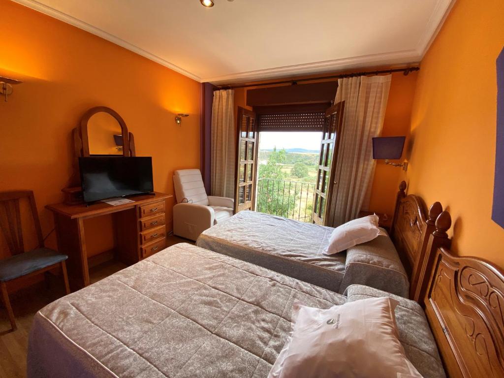 プエブラ・デ・サナブリアにあるTierra De Lobosのベッド2台とテレビが備わるホテルルームです。