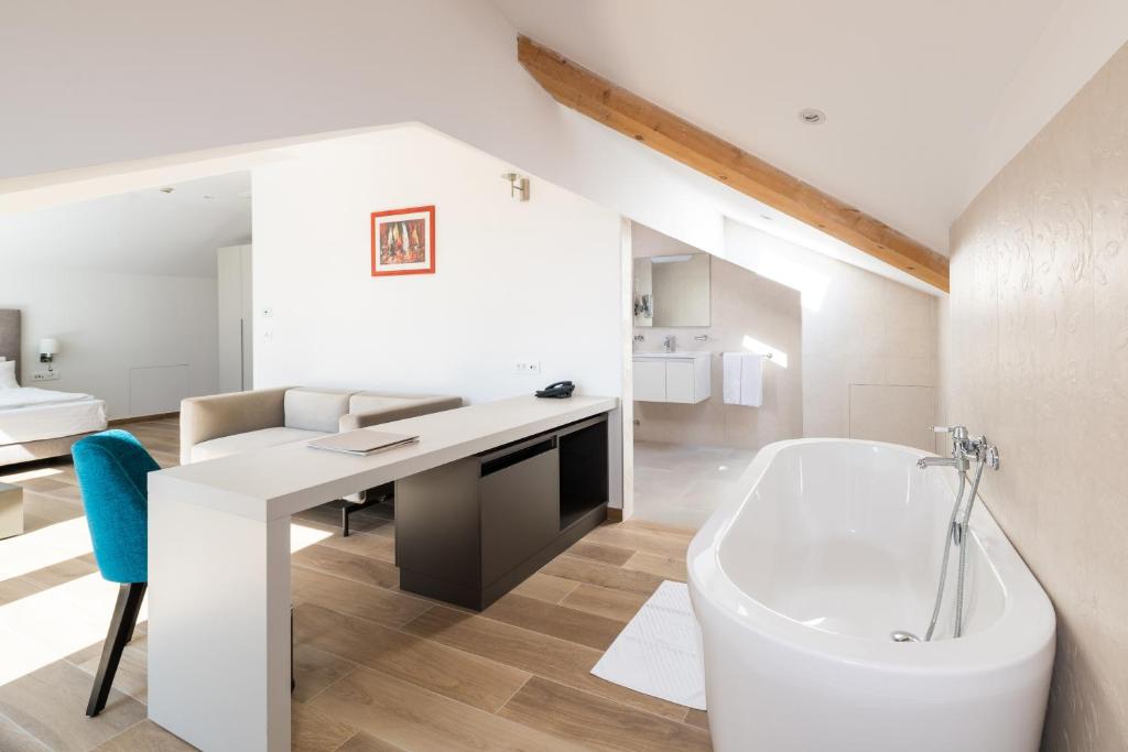 a bathroom with a tub and a desk and a sink at BO Hotel Palazzo in Poreč