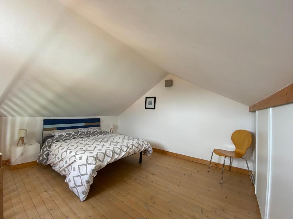 um quarto com uma cama e uma cadeira num sótão em CENTRE CHATELAILLON GRAND LOFT ** 100m DE LA PLAGE em Châtelaillon-Plage