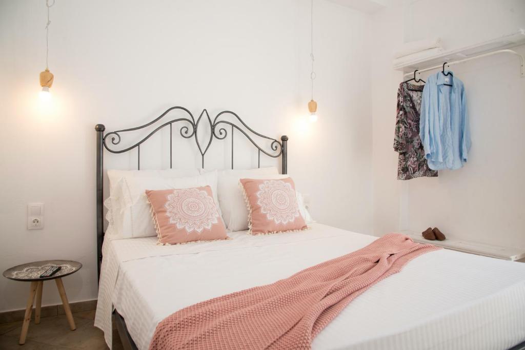 a bedroom with a white bed with pink pillows at Unique Anoi House - In the Heart of Skyros Village in Skiros