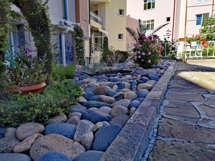 einen Steinweg mit Felsen, Pflanzen und Gebäuden in der Unterkunft Guest House Dimovi in Sozopol