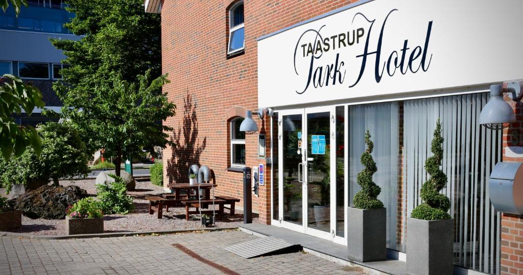 una tienda frente a un edificio de ladrillo con una mesa al aire libre en Taastrup Park Hotel, en Tåstrup