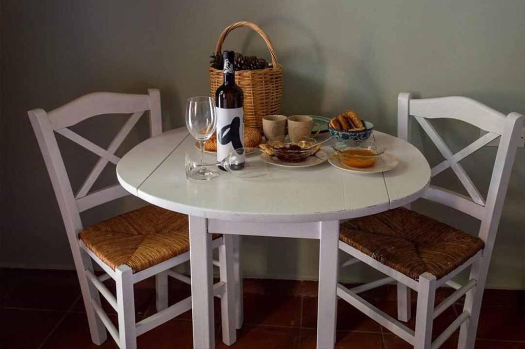 a white table with two chairs and a bottle of wine at ''Arsinoe'' cosy guesthouse in Methana