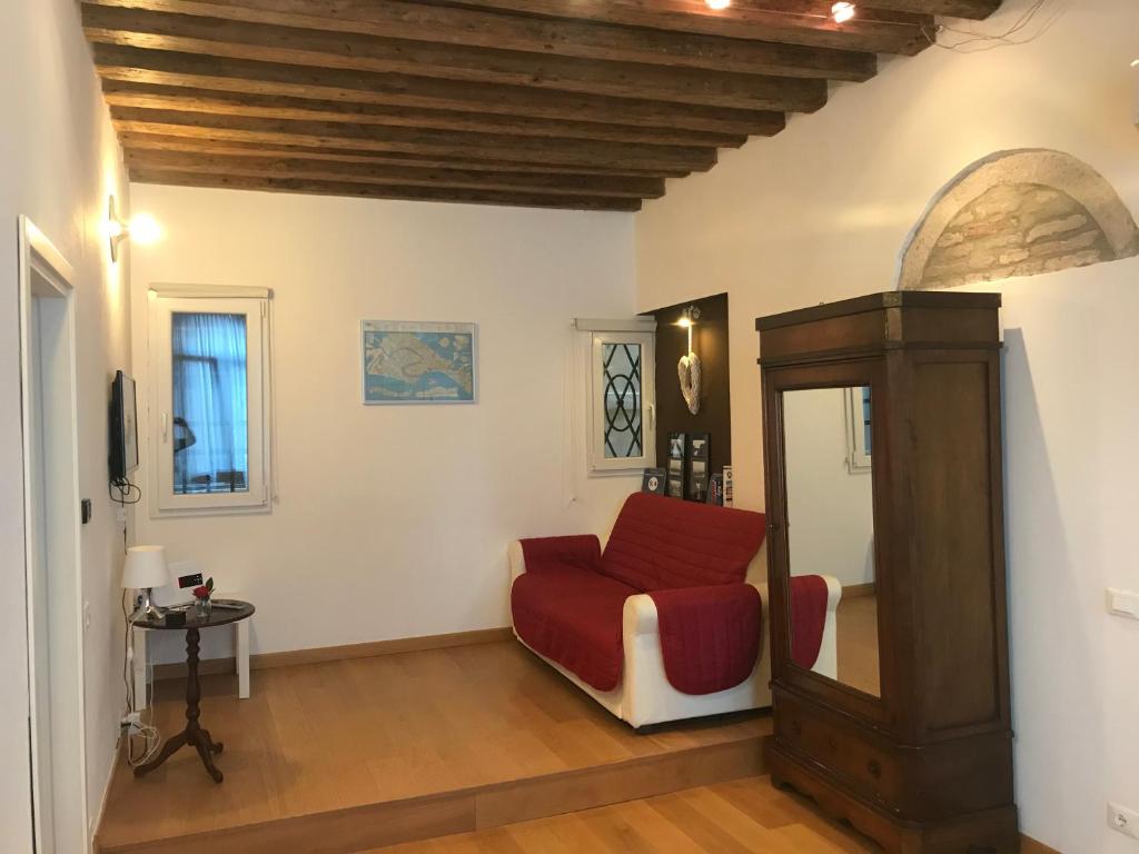 a living room with a red chair and a mirror at Appartamento Ghetto Novissimo in Venice