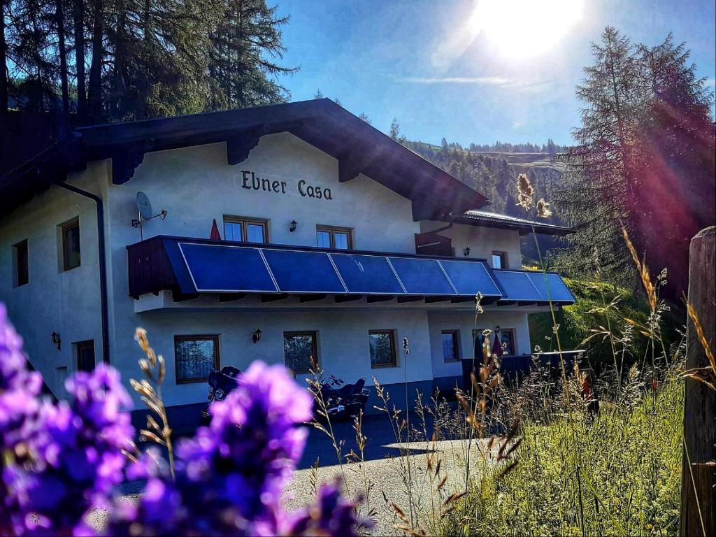 a building with a blue roof with the sun in the background at Ebner Casa in Heiligenblut
