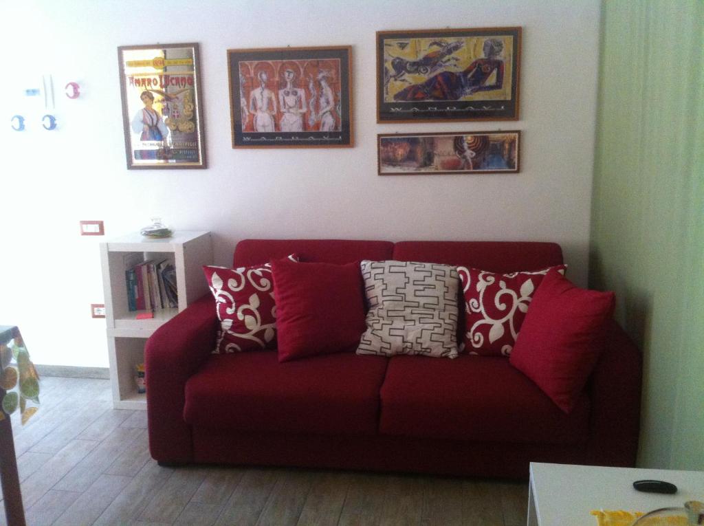 un divano rosso in un soggiorno con foto appese al muro di La Casa del Giglio a Matera