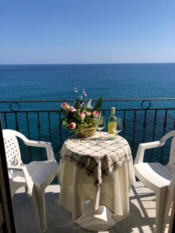 - une table avec des fleurs et des bouteilles de vin sur le balcon dans l'établissement La Casa Sulla Scogliera, à Cefalù