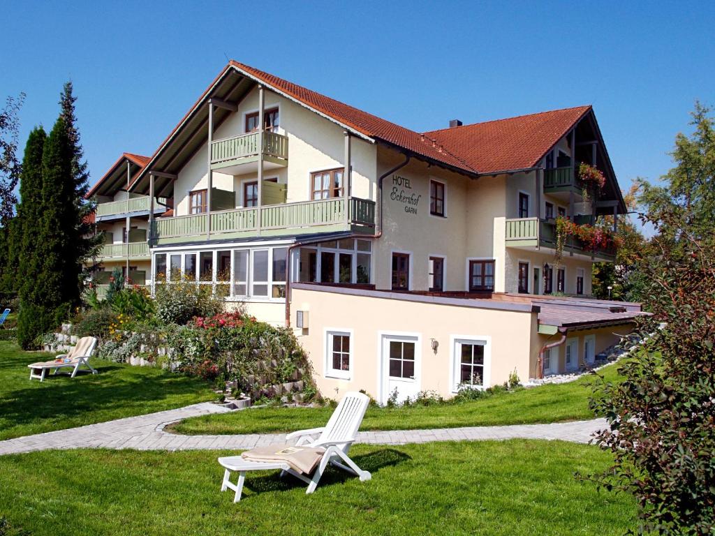 バート・ビルンバッハにあるXundheits Hotel Garni Eckershofの芝生の椅子2脚が前に置かれた大きな建物