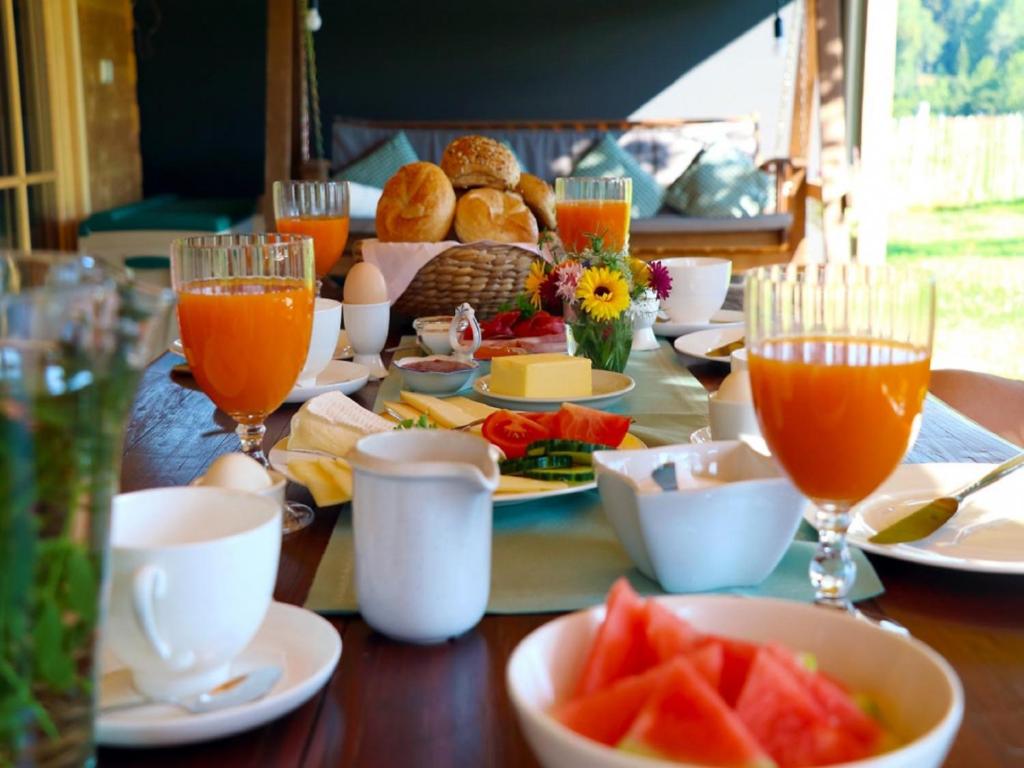 a table topped with plates of food and glasses of orange juice at Ferienwohnungen Berger in Scheidegg